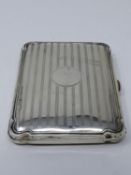 An leather lined Edwardian silver cigarette case with engine turned linear decoration, circular