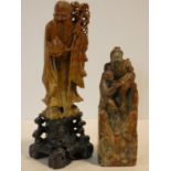 A Chinese carved soapstone figure of Shou Lao standing on naturalistic rocky base and another