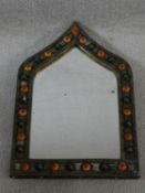 An Indian brass and metal mirror with moulded orange and black bead studded detailing and repousse