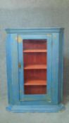 A 19th century distressed painted corner cupboard with glazed door enclosing shelves. H.125 W.87 D.