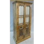 An Eastern teak hall cupboard with pair of carved panel doors fitted with grille enclosing