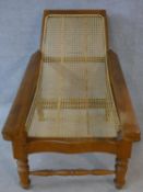 A Colonial style teak framed reclining planter's chair with caned back and seat and foldout foot