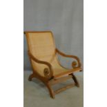 An Indian teak Colonial style planters chair with scroll arms and wicker upholstered back and