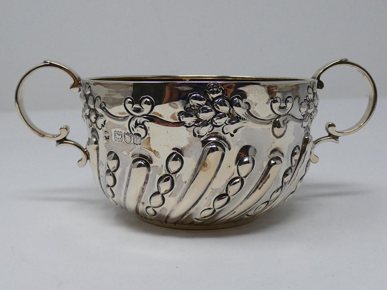 A two handled Victorian repousse design silver porriger with floral design and scrolling handles. - Image 2 of 6