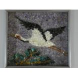 A Japanese framed gemstone pebble mosaic of a Red Crowned Crane flying over trees, set with