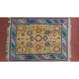 An Eastern rug with all over stylised floral motifs on a sand ground contained by geometric multi