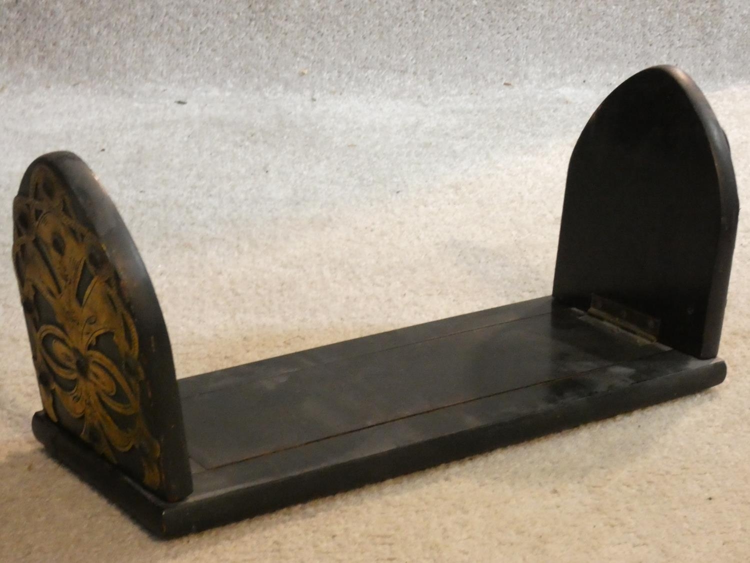 A Victorian ebonised desk top book slide with engraved pierced brass bound arched ends. 33x13cm