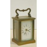 An antique brass carriage clock with white enamel dial and chamfered glass panels. With key. H.15