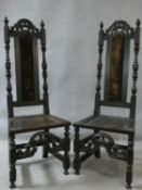 A pair of 17th century oak side chairs with carved arched back rails above solid panel seats on