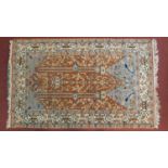 A large Persian style prayer rug with all over floral decoration on a rouge ground within stylised