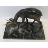 A pair of spelter Art Deco male and female gazelles mounted on a black and white veined marble base.