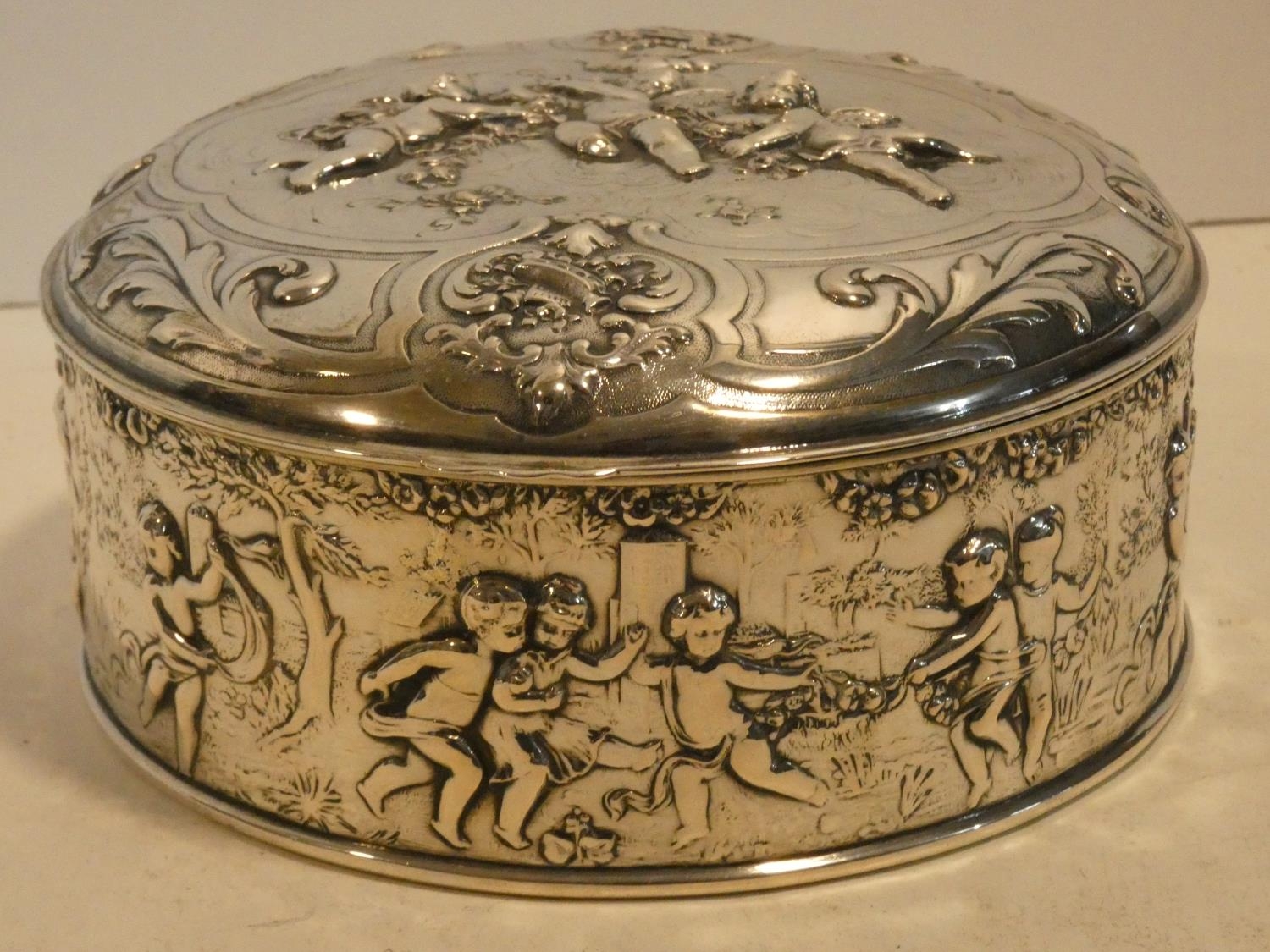 A Continental white metal hinged lidded caddy with gilded interior decorated with repousse repeating