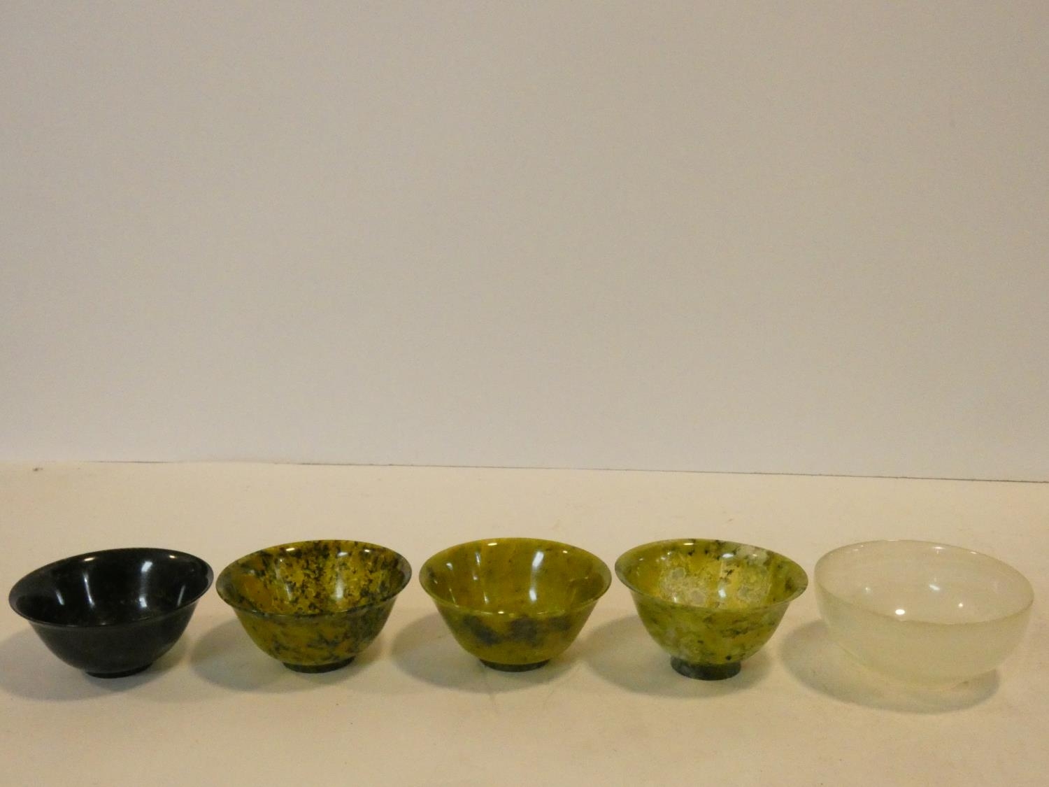 A set of four Chinese carved Spinach Jade flared rim, footed bowls along with a banded alabaster