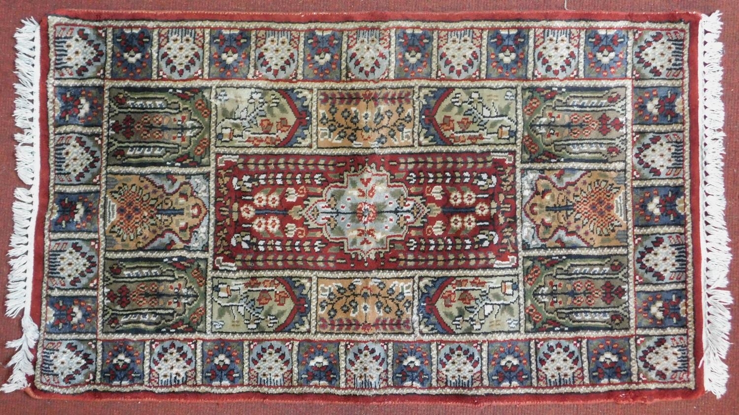 A Bachtiar rug with central pole medallion on burgundy ground within floral panels. 62x112cm