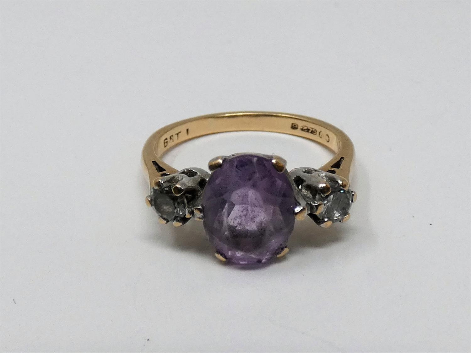 A 9ct yellow gold and white metal three stone ring, set with purple and white paste stones. Shank