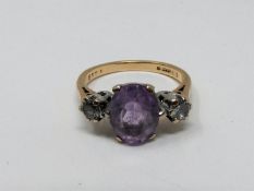 A 9ct yellow gold and white metal three stone ring, set with purple and white paste stones. Shank