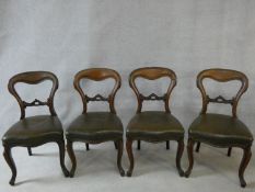 A set of four mid Victorian mahogany balloon back dining chairs with deep green leather stuffover