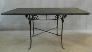 A circular wrought iron conservatory table on swept supports with heavy slate top. H.74 W.150 D.94cm