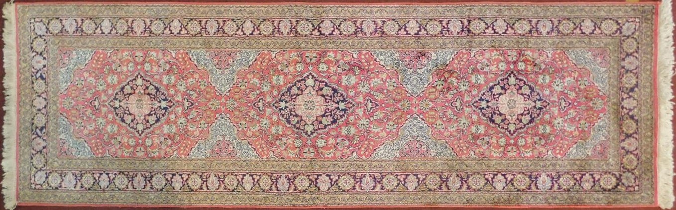 A Persian part silk runner with repeating triple medallions and scrolling floral decoration on a