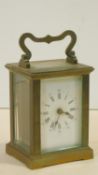An antique brass carriage clock with white enamel dial and chamfered glass panels. With key. H.15