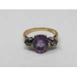 A 9ct yellow gold and white metal three stone ring, set with purple and white paste stones. Shank