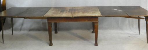 An early 20th century oak extending dining table with central leaf fitted to the underside and