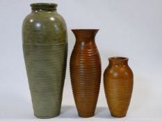 A tall ceramic glazed vase of bulbous form along with two turned and polished wooden vases. H.