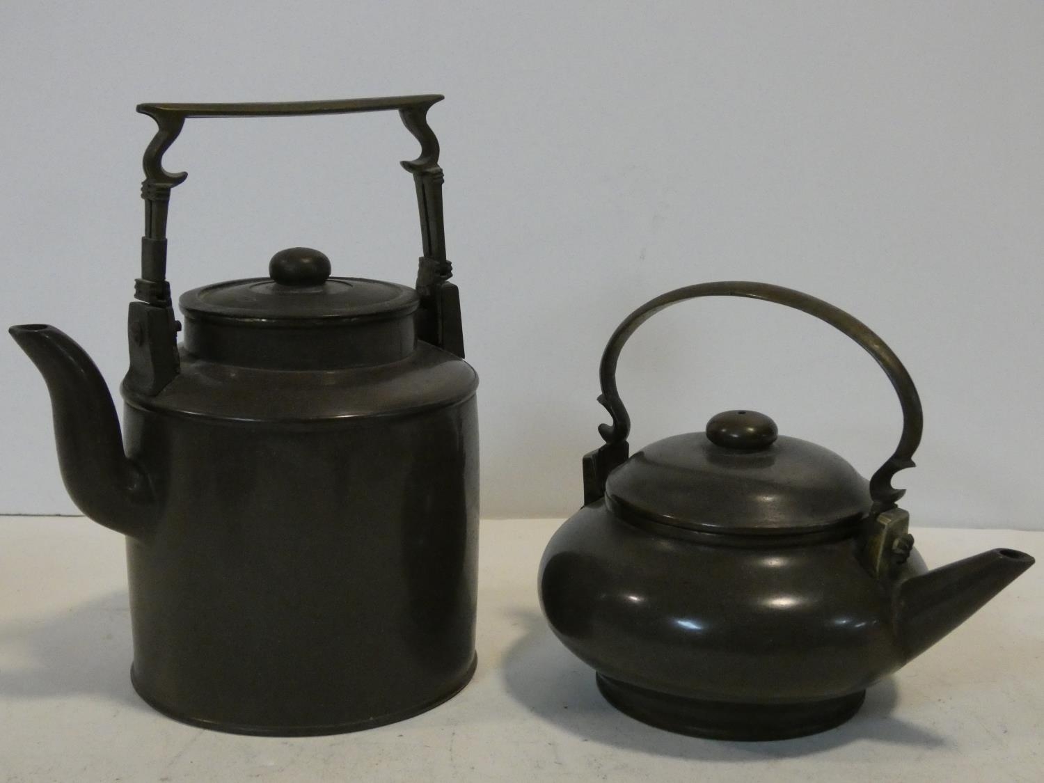 Two Chinese Yixing Pottery teapots with cast brass handles and finials and banding around the edges,