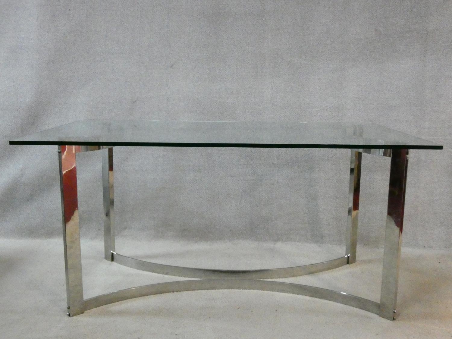 A vintage dining table in the style of Gavina, the heavy plate glass top resting on a shaped