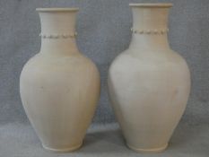 A pair of large floor standing earthenware Persian Hamadan storage vessels with studded collars. H.