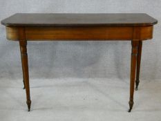 A 19th century D-end mahogany console table on turned tapering supports terminating in brass cap