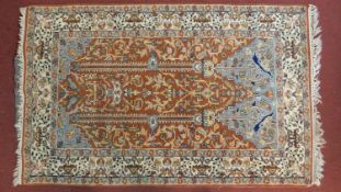 A large Persian style prayer rug with all over floral decoration on a rouge ground within stylised