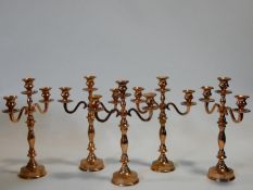 A collection of five copper effect metal three branch table candelabras. H.40cm