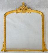 A 19th century style gilt framed overmantel mirror with scrolling cresting to the arched framed