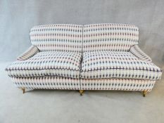 A Howard style three seater sofa in geometric textile upholstery on turned tapering Victorian style