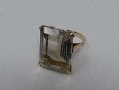 A 9ct yellow gold and citrine dress ring. Set with a rectangular mixed cut pale yellow stone in a