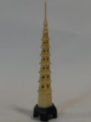 An antique Chinese carved ivory pagoda with spire that unscrews, mounted on an ebonised base. H.27cm