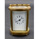 A miniature French brass five glass oval carriage clock with bevelled glass plates, white enamel