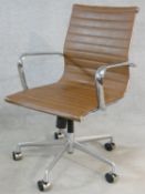 A Charles Eames style swivel office armchair with rise and fall action in light tan leather