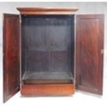An early 19th century figured mahogany wardrobe with stepped moulded pediment above panel doors