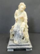 A large carved Eastern soapstone figure of a deity holding a sacred text perched on a rock raised on