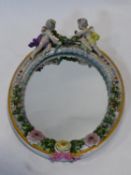 An antique Meissen porcelain oval mirror with bevelled plate in floral encrusted frame surmounted by