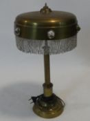 A vintage brass table lamp with glass roundels to the fringed shade on reeded column support. H.