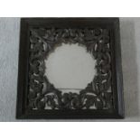 An Eastern teak wall mirror with carved and pierced inner frame. 40x40cm