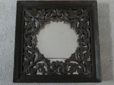 An Eastern teak wall mirror with carved and pierced inner frame. 40x40cm