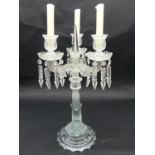 A glass three branch table candelabra with crystal drops on dolphin support. H.50cm