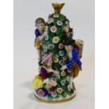 A Chelsea style porcelain perfume bottle with three figures around a spire of flowers and foliage