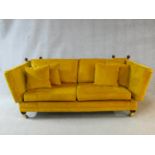 A contemporary Knole sofa in gold upholstery raised on squat square tapering supports on brass cup