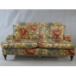 A Howard style sofa in floral upholstery on turned tapering supports terminating in brass and