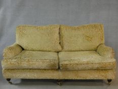 A two seater Howard style sofa in cut floral upholstery on triple squat turned tapering supports